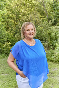 mujer con camisa azul de pie delante de un fondo verde