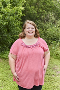 mujer con camisa rosa de pie delante de un fondo verde