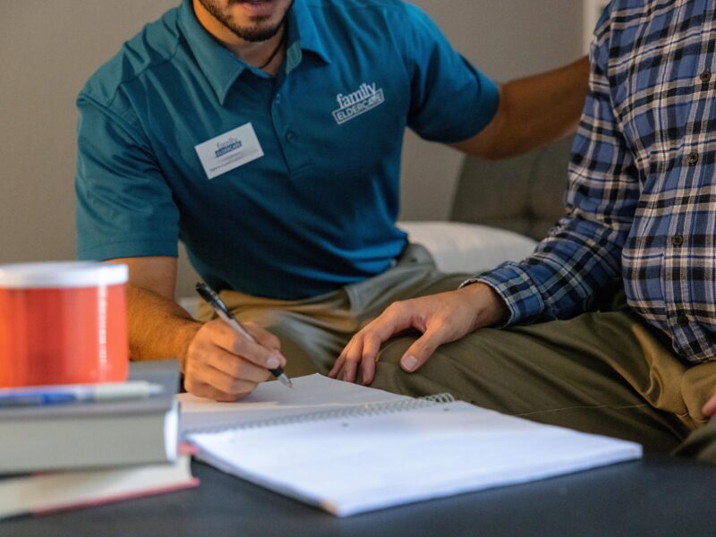 person with pen and paper next to another person