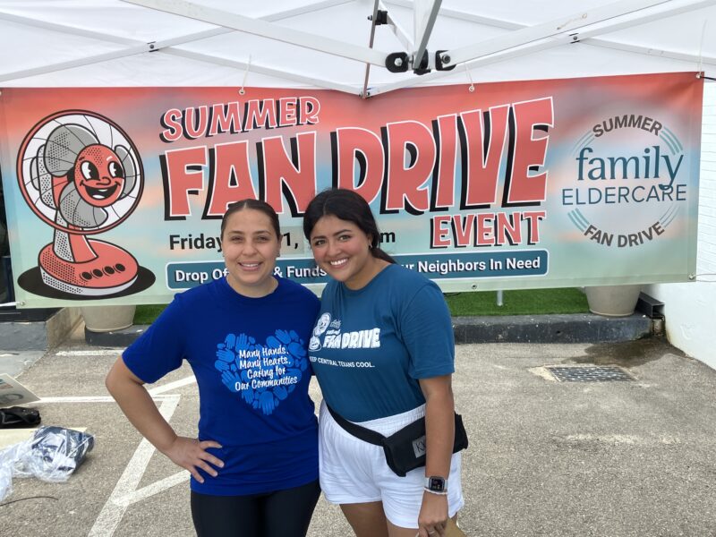 2 people standing in front of Summer fan Drive banner.