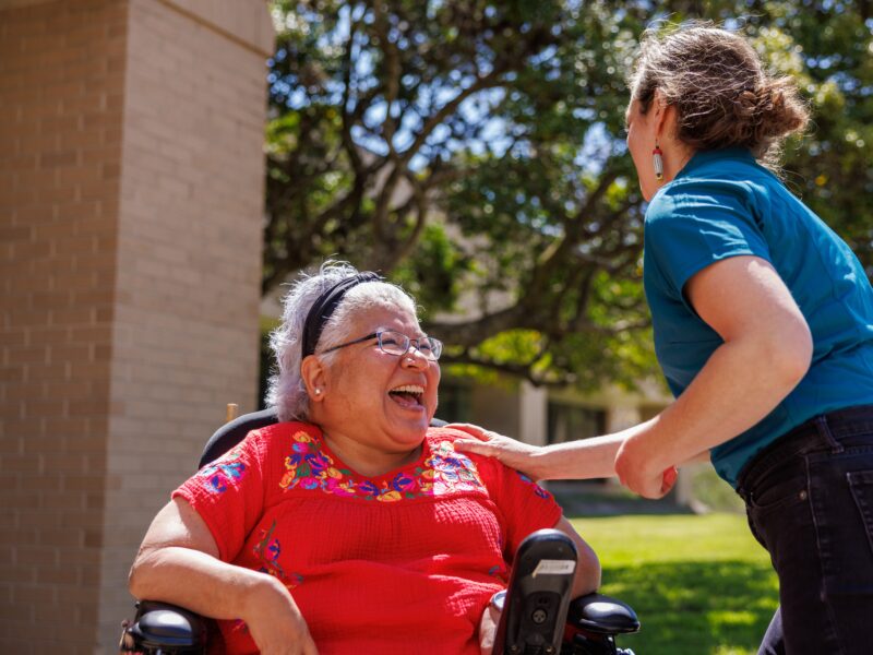 person laughing while another person taps their shoulder
