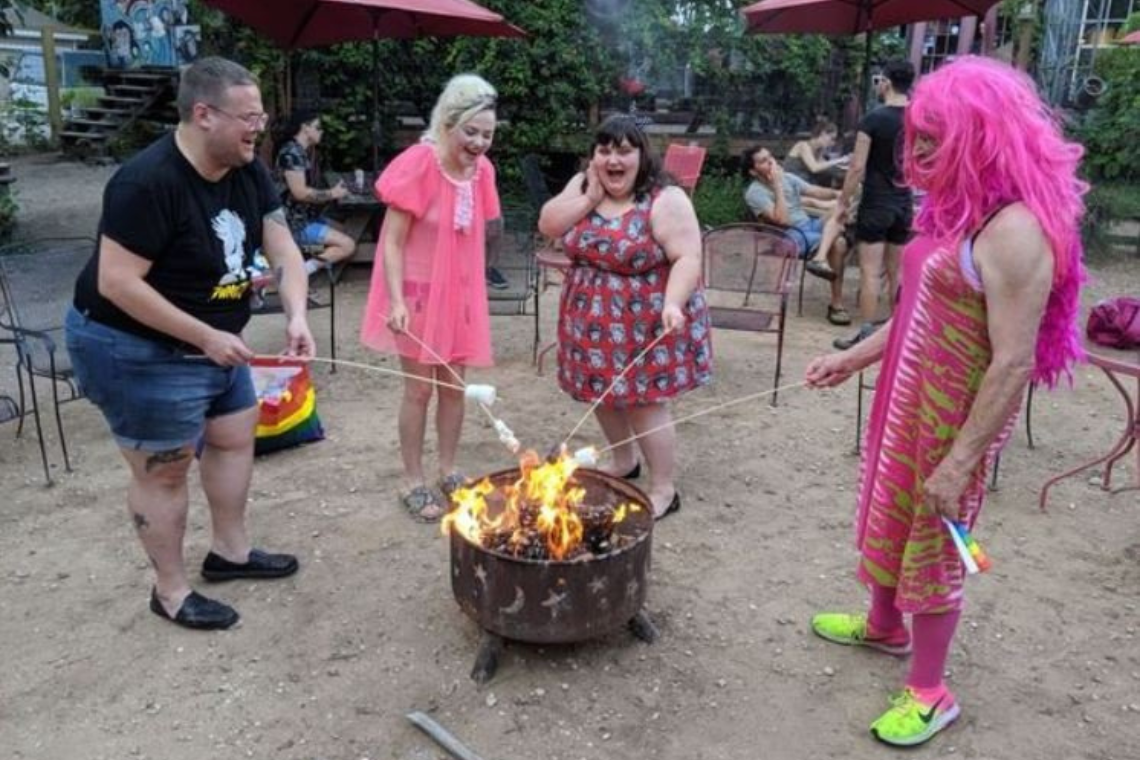 4 people roasting marshmallows around a campfire.